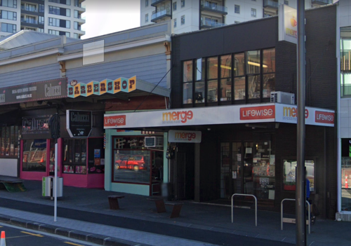 A strip of storefronts with apartment blocks in the background.